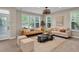 A sunlit living room showcases neutral-toned sofas, a coffee table, decorative pillows, and a decorative ceiling fan at 693 Syracuse St, Denver, CO 80230