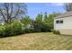 Backyard view of home with green grass, mature trees, and shrubs at 107 S Windsor Dr, Denver, CO 80219