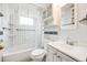 Compact bathroom featuring a tub, toilet, and a sink with a mirrored cabinet, complemented by white tiled walls at 107 S Windsor Dr, Denver, CO 80219