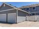 Attached two-car garage with a gray exterior and a white fence leading to the backyard at 19043 E 58Th Ave, Denver, CO 80249