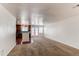Open-concept living area with carpet, white walls, and an eat-in kitchen with wooden cabinets at 19043 E 58Th Ave, Denver, CO 80249