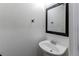 Half bathroom with a vanity sink, a mirror, and decorative hooks on the textured white walls at 19043 E 58Th Ave, Denver, CO 80249