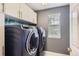 Functional laundry room with modern washer and dryer, overhead cabinets, and a bright window at 9458 S Hackberry Ln, Highlands Ranch, CO 80129