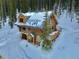Aerial view of a log cabin with a snow covered yard surrounded by trees at 812 High Point Dr, Breckenridge, CO 80424
