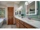 Bathroom featuring a double sink vanity, stylish mirrors, and a separate tub at 767 Tenderfoot Dr, Larkspur, CO 80118