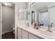 Bright bathroom with dual sinks, chrome fixtures, white cabinets, and dark brown flooring at 9758 Laredo St # 1E, Commerce City, CO 80022