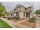 Exterior of townhome featuring stone and tan siding, landscaping, and a covered porch at 9758 Laredo St # 1E, Commerce City, CO 80022