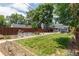 Spacious backyard with green lawn, mature trees, and garden beds by a tall wood fence at 3182 W 29Th Ave, Denver, CO 80211
