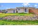 Backyard showcasing the home's exterior with a stone accent wall, vibrant grass and mature landscaping at 598 Arden Cir, Highlands Ranch, CO 80126