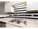 Close up on kitchen sink with granite countertops and stylish black and white backsplash at 18103 E Kentucky Ave # 103, Aurora, CO 80017