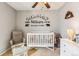 This cozy Bedroom features a crib, rocking chair and custom mountain theme wall decor creating a charming space at 16277 E Arkansas Dr, Aurora, CO 80017