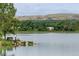Scenic lake view with trees, a distant home, and rolling hills at 1536 S Field Ct, Lakewood, CO 80232