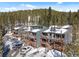A complex of townhomes with balconies, set against a backdrop of snow-covered trees and a clear blue sky at 112 Illinois Gulch Rd # 6, Breckenridge, CO 80424