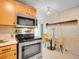 Kitchen featuring stainless steel range with light wood cabinets, dining table and neutral wallpaper at 1050 N Lafayette St # 408, Denver, CO 80218