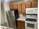 Functional kitchen equipped with stainless steel refrigerator, white range and microwave, plus wood cabinets at 707 W 96Th Ave # 9, Thornton, CO 80260