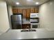 Cozy kitchen features stainless steel refrigerator, white appliances, and oak-style cabinetry at 707 W 96Th Ave # 9, Thornton, CO 80260