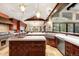 Vaulted kitchen with central island, stone accents, stainless appliances, and cherry cabinets at 1 Canon Pl, Greenwood Village, CO 80111