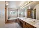 Bright bathroom features a large mirror, double sinks, soaking tub, and glass door shower at 7354 S Robb St, Littleton, CO 80127