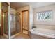 Bathroom features a soaking tub, glass door shower, and window at 7354 S Robb St, Littleton, CO 80127