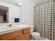 Bright bathroom with a wood vanity, white countertop and shower with a plaid curtain at 7354 S Robb St, Littleton, CO 80127