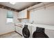 Functional laundry room features tile floor, cabinets, sink and modern washer and dryer at 7354 S Robb St, Littleton, CO 80127