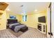 A staged basement bedroom featuring neutral decor, a fireplace, TV, and ample lighting for a cozy and inviting space at 1824 Asoka St, Strasburg, CO 80136