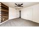 Bright bedroom with unique wood accent wall, neutral carpet, and ceiling fan for added comfort at 1824 Asoka St, Strasburg, CO 80136