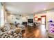 Inviting living room featuring hardwood floors that transition to the kitchen with bar seating and stainless steel appliances at 1824 Asoka St, Strasburg, CO 80136