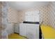 Compact laundry room with washer, dryer, sink and bright, patterned wallpaper at 2949 Vivian St, Wheat Ridge, CO 80215
