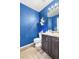 Stylish bathroom featuring a modern vanity, elegant mirror, and blue accent wall at 14803 E 117Th Pl, Brighton, CO 80603