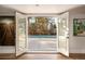 View from inside looking at a patio with a tennis court framed by double glass doors and artwork at 39 Sedgwick Dr, Cherry Hills Village, CO 80113