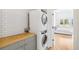 Bright laundry room featuring a stacked washer and dryer next to a wooden countertop at 421 Saint Paul St, Denver, CO 80206