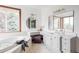 A spacious bathroom featuring a large tub, vanity, and a round mirror at 10260 Longview Dr, Lone Tree, CO 80124