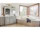 A luxurious bathroom featuring a large soaking tub, vanity, and two windows allowing for natural light at 10260 Longview Dr, Lone Tree, CO 80124