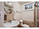 This cozy bathroom features tiled walls, a round mirror, and a window above the toilet at 3107 S Wolff St, Denver, CO 80236