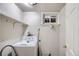 This laundry room features a white washing machine, a window and shelving for storage at 3107 S Wolff St, Denver, CO 80236