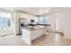 Bright kitchen boasts stainless appliances, island, and white cabinets with dark countertops at 712 N Bently St, Watkins, CO 80137