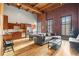 Open-concept living room showcasing exposed brick, wood beams, a modern kitchen, and large windows with natural light at 1450 Wynkoop St # 3F, Denver, CO 80202