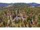 A high aerial view of a home, surrounded by trees, nestled into the nearby foothills of a mountain at 32173 Soda Creek Dr, Evergreen, CO 80439