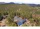 Aerial shot of house surrounded by a thick forest with a view of the mountains in the background at 32173 Soda Creek Dr, Evergreen, CO 80439