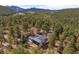 An aerial view of a house surrounded by a forest, showing mountains in the background at 32173 Soda Creek Dr, Evergreen, CO 80439