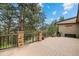 Wooden deck features stone pillars, iron railing, and a natural landscape view from the back of the house at 32173 Soda Creek Dr, Evergreen, CO 80439