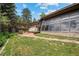 Spacious backyard featuring a patio area, lush green lawn, mature trees, and stone accents, perfect for outdoor living at 32173 Soda Creek Dr, Evergreen, CO 80439