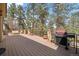 Expansive wooden deck with a grill, stone pillars, and scenic views of towering trees at 32173 Soda Creek Dr, Evergreen, CO 80439