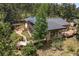 Eco-friendly home featuring solar panels, lush landscaping, deck, and outdoor pergola with a patio area at 32173 Soda Creek Dr, Evergreen, CO 80439