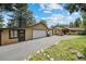 Exterior of home shows large garage, mature trees, landscaping, and a long driveway at 32173 Soda Creek Dr, Evergreen, CO 80439