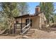 Quaint cabin featuring a covered porch with seating and natural rock outcroppings at 32173 Soda Creek Dr, Evergreen, CO 80439