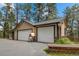 Three car garage with an outdoor pizza oven on a spacious driveway surrounded by mature trees at 32173 Soda Creek Dr, Evergreen, CO 80439