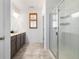 Bathroom featuring double sink vanity, tile flooring, walk-in shower and window with wood shutters at 3015 Pershing St, Strasburg, CO 80136