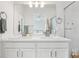 Bright bathroom with double sinks, white cabinetry, a large mirror, and tiled shower at 17039 E Exposition Dr, Aurora, CO 80017